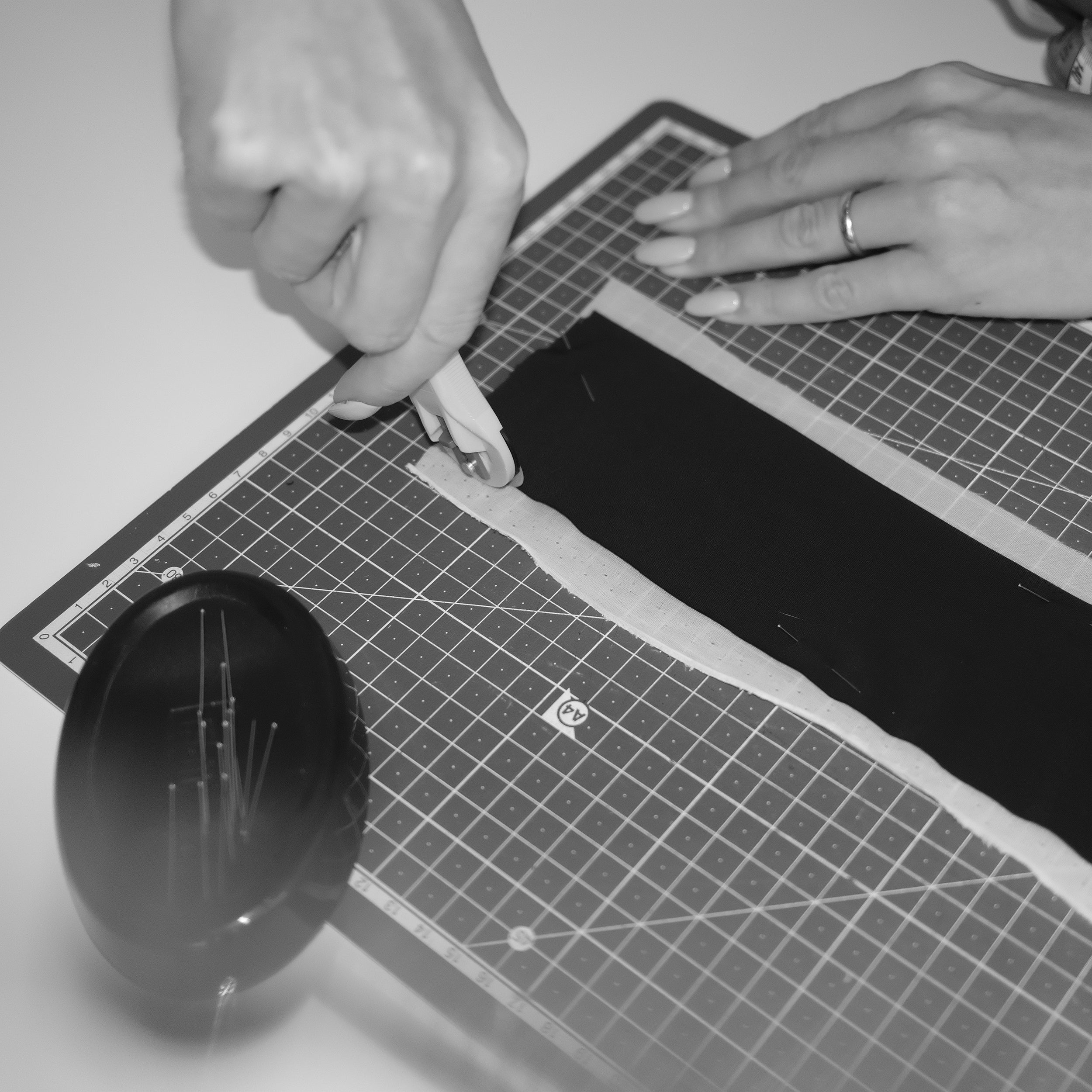 Person using a tool on a black object on a grid cutting mat. INA KESS atelier in Switzerland.