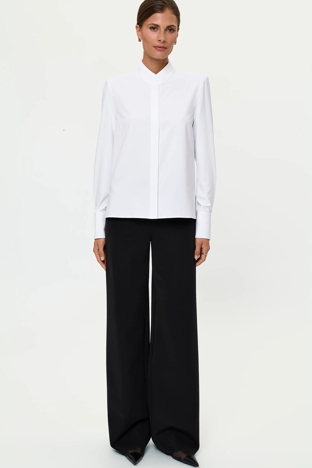 Full-length front view of the white LEONTA shirt styled untucked with black wide-leg LIORA pants, showing the clean blouse silhouette and relaxed pant fit.
