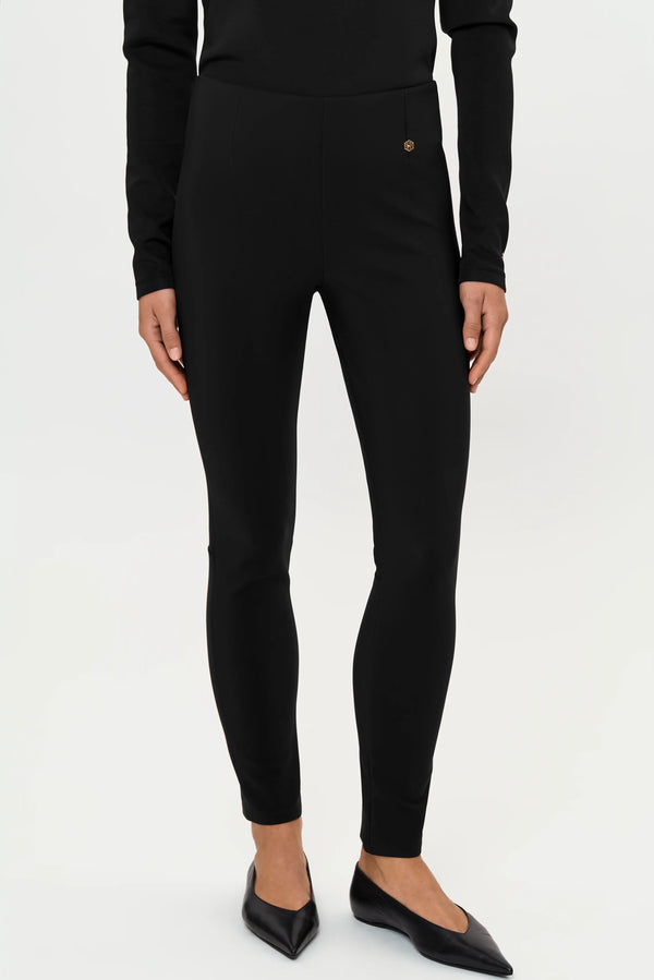 Front close-up of black stretch pants showing the slim fit and gold logo at the hip.