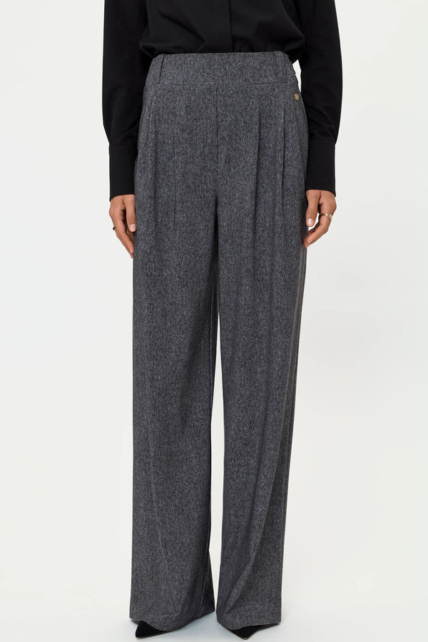 Close-up of grey wide-leg stretch pants showing front pleats, high waist, and textured fabric.